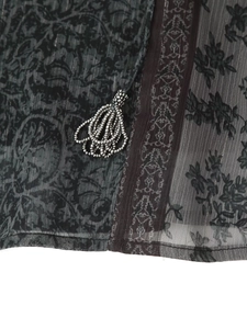 Detailaufnahme von Metallperlen und ethnischem Muster auf dem bedruckten V-Ausschnitt Kleid
