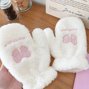 Close-up of white plush gloves featuring pink bow embroidery and soft fleece texture