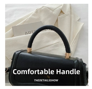 Detail of black leather handbag with round handle and gold-tone FASHION metal hardware