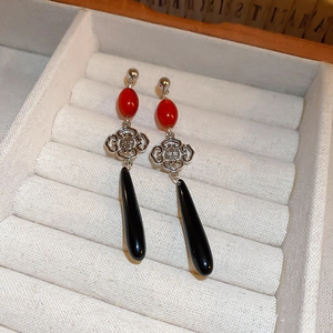 Detail of vintage Chinese knot earrings with red beads and black teardrop pendants