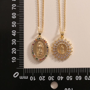 Detail view of gold Virgin Mary pendants with colorful zircons next to a measuring tool