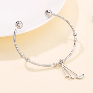 Detailed close-up of silver celestial moon and star charms on an open metal cuff bracelet