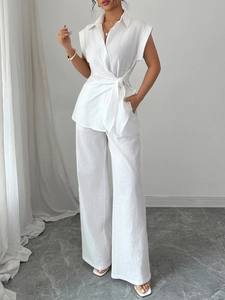 Elegant white two-piece linen set with sleeveless waist-tie shirt and wide-leg trousers