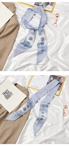 Detail of light blue silk scarf with planet patterns and space-themed prints on satin background