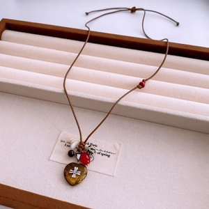 Gros plan du pendentif cœur en œil de tigre avec croix sur collier vintage en corde cirée