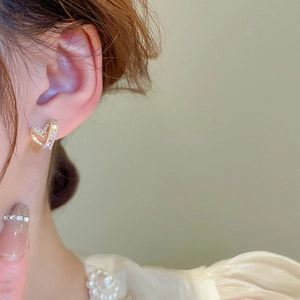Macro shot of gold-plated hollow heart earrings with shimmering zircon stones on model