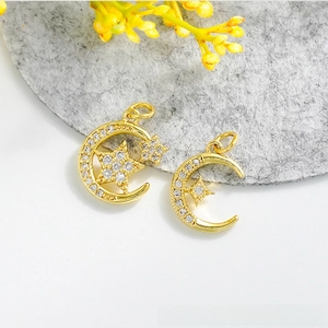 Vue détaillée de breloques lune et étoile dorées à l'or 18 carats avec oxydes de zirconium