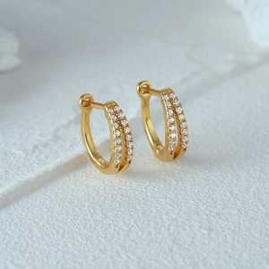 Macro shot of gold-plated double-row pavé huggie earrings with sparkling crystals