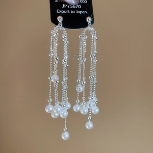 Detail of silver tassel earrings with multiple white pearls and shiny metal chains