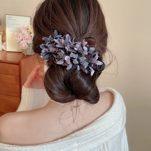 Detailed view of an elegant purple floral hair clip styled on a low bun hairstyle