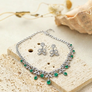 Close-up of bow knot jewelry set with green teardrop gemstones and diamonds