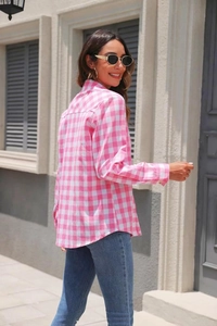 Detail of pink plaid button-up shirt cuff and lightweight fabric texture on model