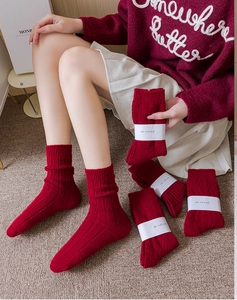 Close-up of thick red knitted socks with cozy texture and festive paper packaging