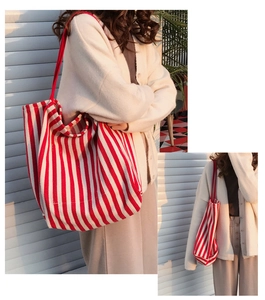 Detailed view of large capacity red and white striped canvas tote bag worn by a model