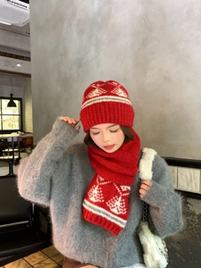 Dettaglio del set natalizio con cappello e sciarpa rossi e motivi jacquard di fiocchi