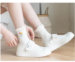 Detail of white cotton socks with tulip embroidery paired with thick-soled Mary Jane shoes