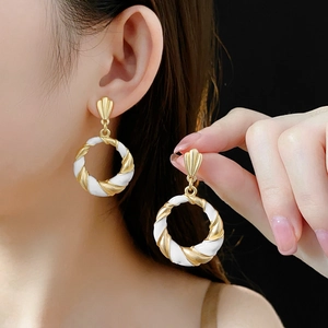 Detailed view of model wearing vintage twisted geometric earrings in gold and white