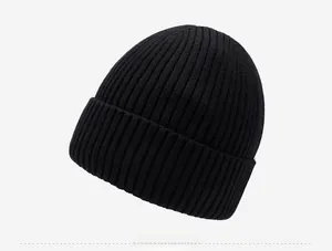 Detailed side view of black ribbed knit beanie with silver mountain emblem logo