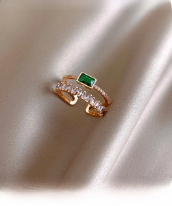 Detail of double-layer gold-plated ring featuring a rectangular emerald green gemstone