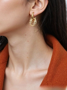 Close-up of gold-plated crisscross hoop earrings with pavé cubic zirconia on model