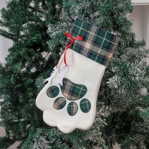 Chaussette de Noël en forme de patte avec motifs à carreaux sur un sapin de Noël enneigé