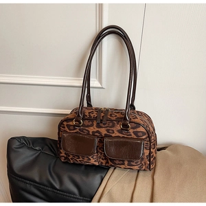 Detail of leopard print suede tote bag featuring brown faux leather front pockets and straps