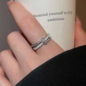 Detail of silver double-layered crisscross ring with zircons and floral centerpiece