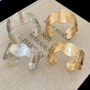 Macro shot of geometric spiral textured open bangles in gold and silver finish