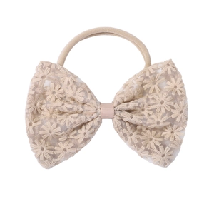 Close-up of beige lace bow headband with delicate daisy embroidery and soft nylon band