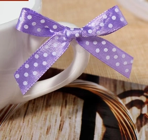 Detail of purple polka dot ribbon bow used as decorative ornament on white ceramic cup handle