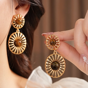 Close-up of vintage golden drop earrings with brown tiger eye stones in retro style