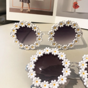 Detail of round transparent frame sunglasses with white daisy flowers and purple lenses