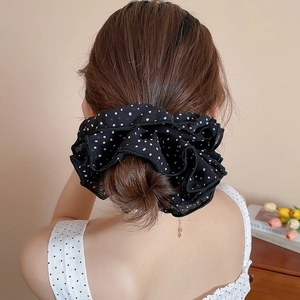 Detailed view of black polka dot oversized scrunchie styled on a woman's bun hairstyle