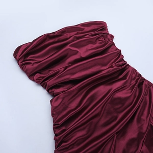 Detail von burgunderrotem Satinstoff mit plissierter Textur und glänzendem Finish am trägerlosen Kleid
