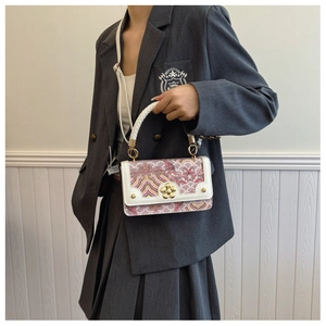 Detailweergave van de witte crossbodytas met roze patroon en bloemsluiting op een model
