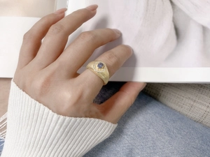 Detail of vintage brushed gold ring with oval tanzanite and diamond halo on model