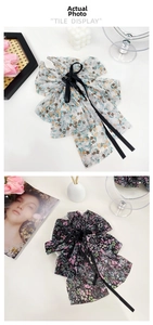 Detailed close-up of large floral chiffon bow hair claws with long elegant ribbons