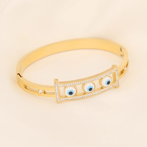 Gold evil eye bracelet with white rhinestones on beige silk background, luxury fashion style