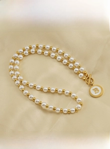 Macro detail of 18K gold stainless steel letter B pendant with pearl beaded chain