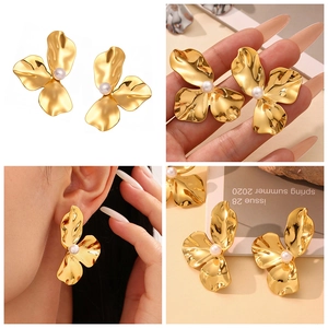 Nahaufnahme der goldenen Blumenohrringe mit gefalteten Blüten und Perlendetail