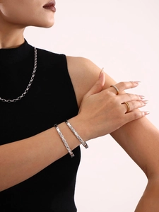 Silver geometric modular bangle in stainless steel shown on a model's wrist