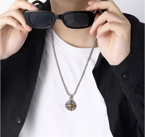Detail of compass star pendant with box chain on a model wearing casual black outfit