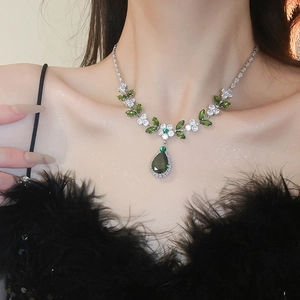 Dettaglio della collana foglia d'argento con zircone a goccia verde sulla modella