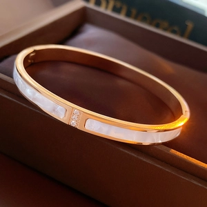 Close-up of rose gold bangle with white shell inlay and three sparkling zircon details