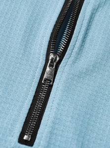 Close-up of silver metal zipper and blue knit fabric texture on men's polo shirt