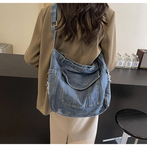 Vue détaillée d'un sac à bandoulière en denim bleu avec bords effilochés et grande taille