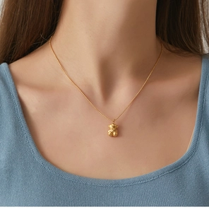 Detailed view of a 3D faceted gold bear pendant on a delicate bead chain worn on neck