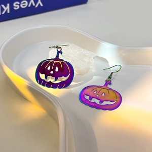 Macro detail of pumpkin Halloween earrings with iridescent metallic gradient finish