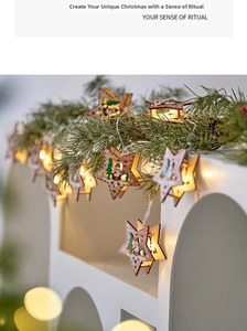 Detail of wooden star LED string lights with Santa patterns on snowy pine branches