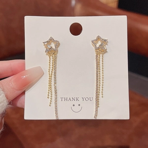 Detail shot of elegant gold star earrings with sparkling crystals and long chain tassels